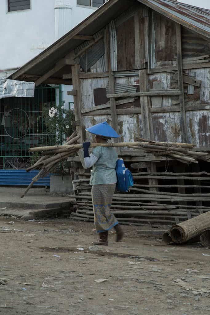 woman carrying long wood sticks