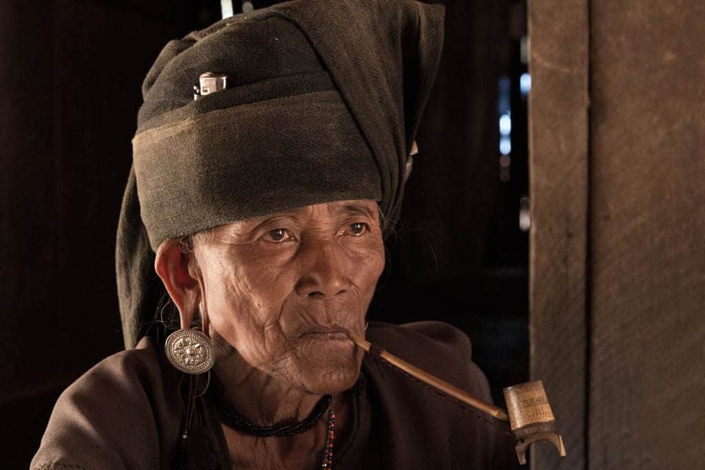 A tribal woman smoking long pipe Myanmar