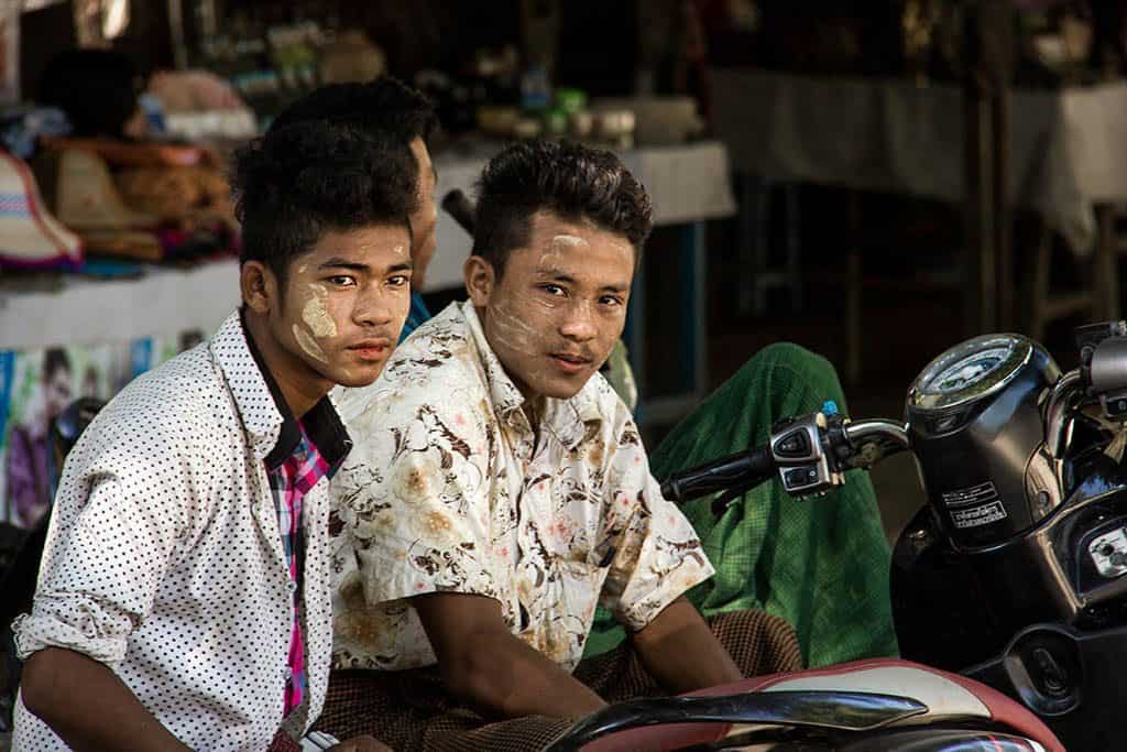 two men near a bike with thanaka on their faces