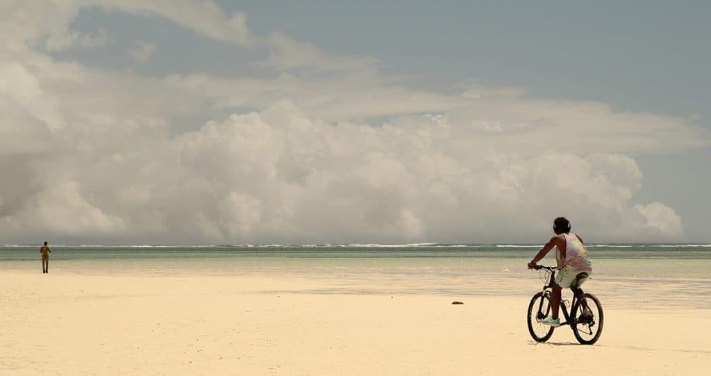 a man riding his bicycle on the beach
