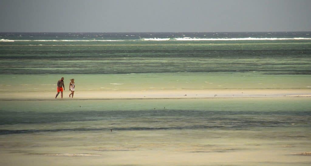 man and woman walking in the shallow water