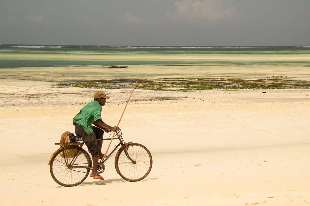 A man riding bicycle on the beach