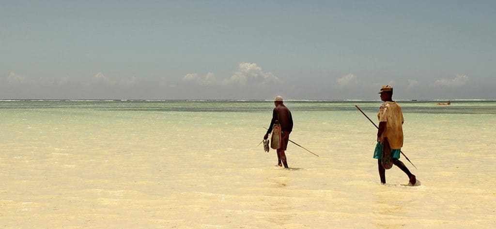 two fishermen walking in the crystal clear water