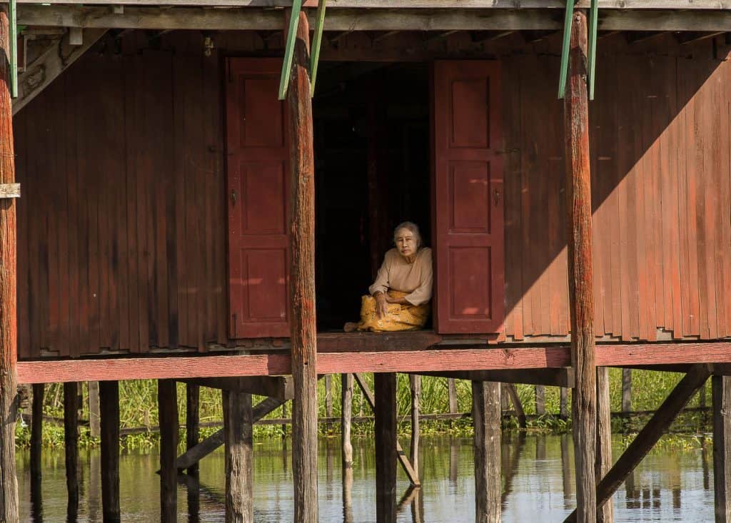 A woman sitting at the front door of her house, Inle Lake