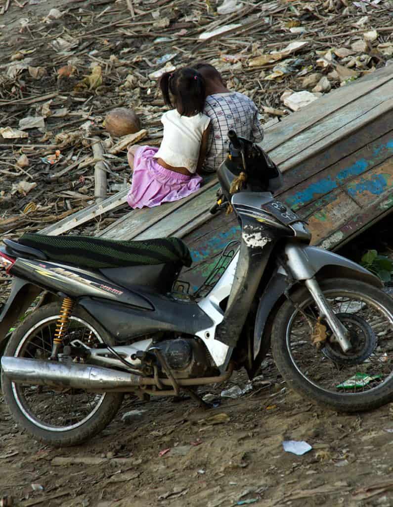 two kids sitting together in front of a motorbike