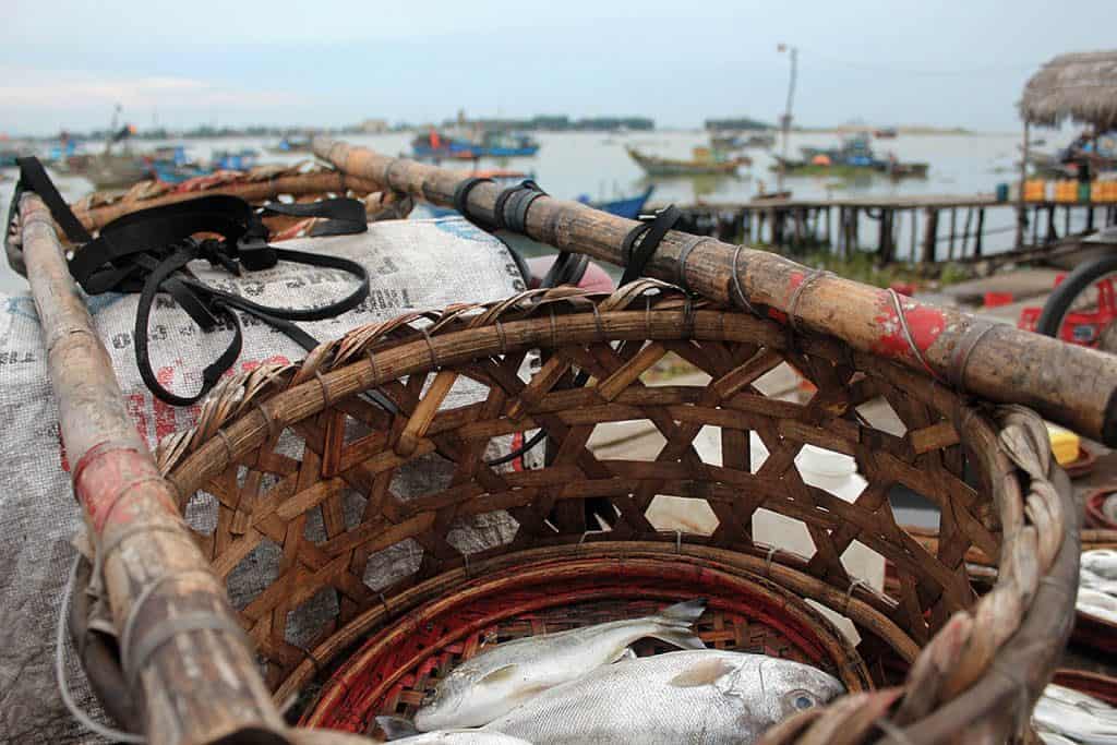 basket with fish and fishing boats faraway