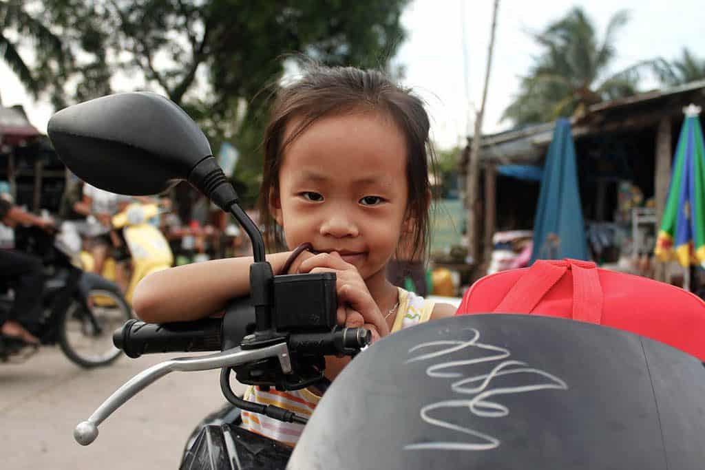 a Vietnamese girl leaning on a motorbike
