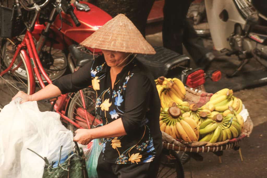 A woman with a bicycle loaded with Bananas