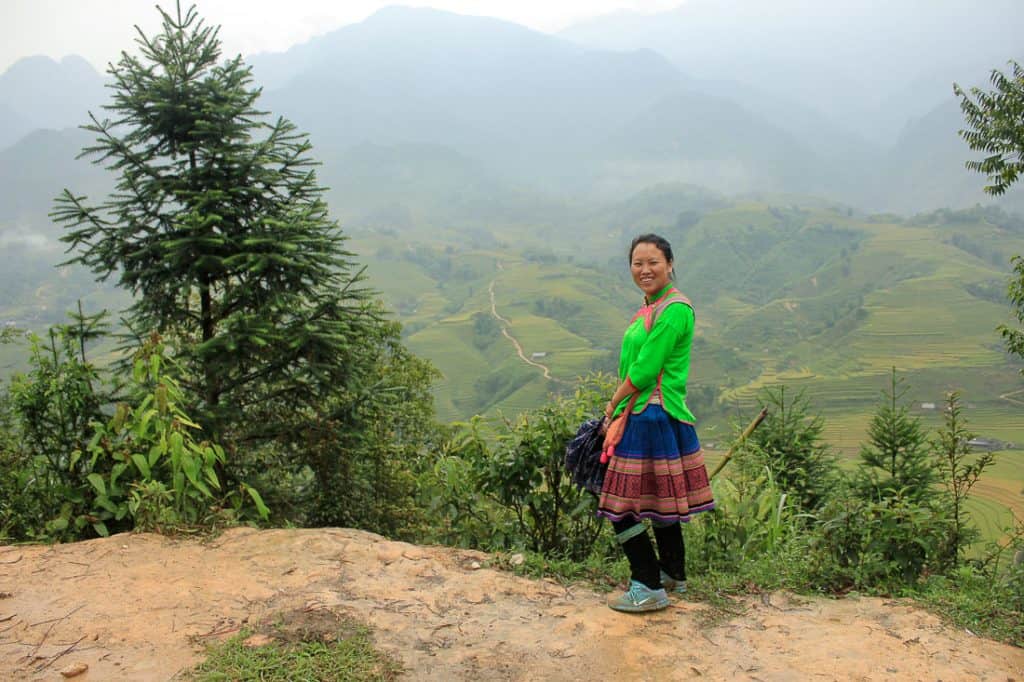 A woman dressed in local clothes and behind her Sapa's rice fields