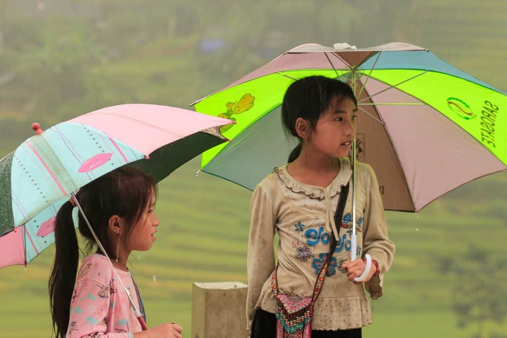 שתי בנות עומדות בגשם עם מטריות