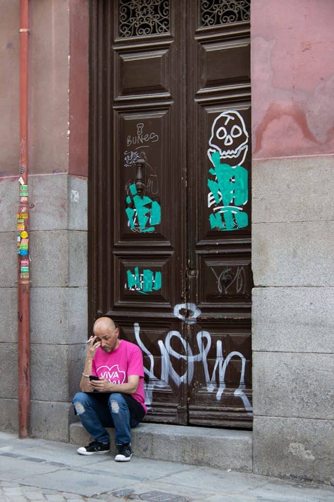 a man sitting on a side walk in madrid