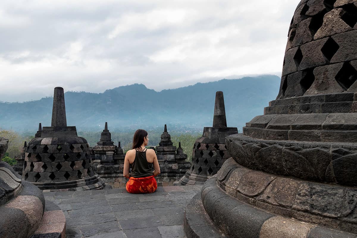 a woman watching the sunrise in borobudur temple