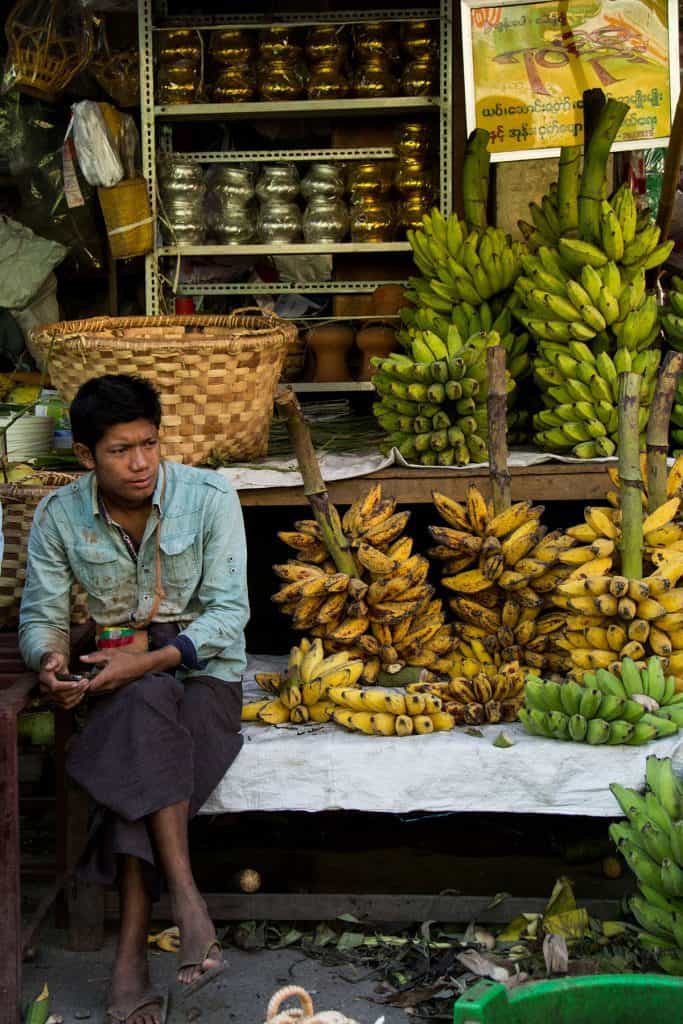 man sitting next to bananas