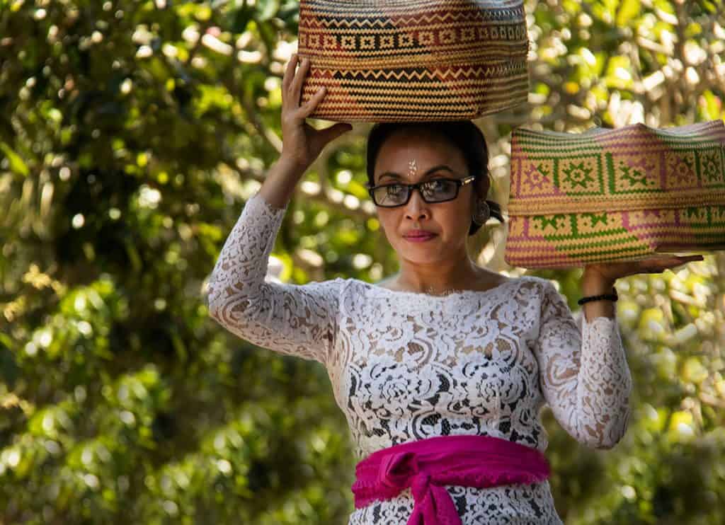balinese woman carrying colorful baskets
