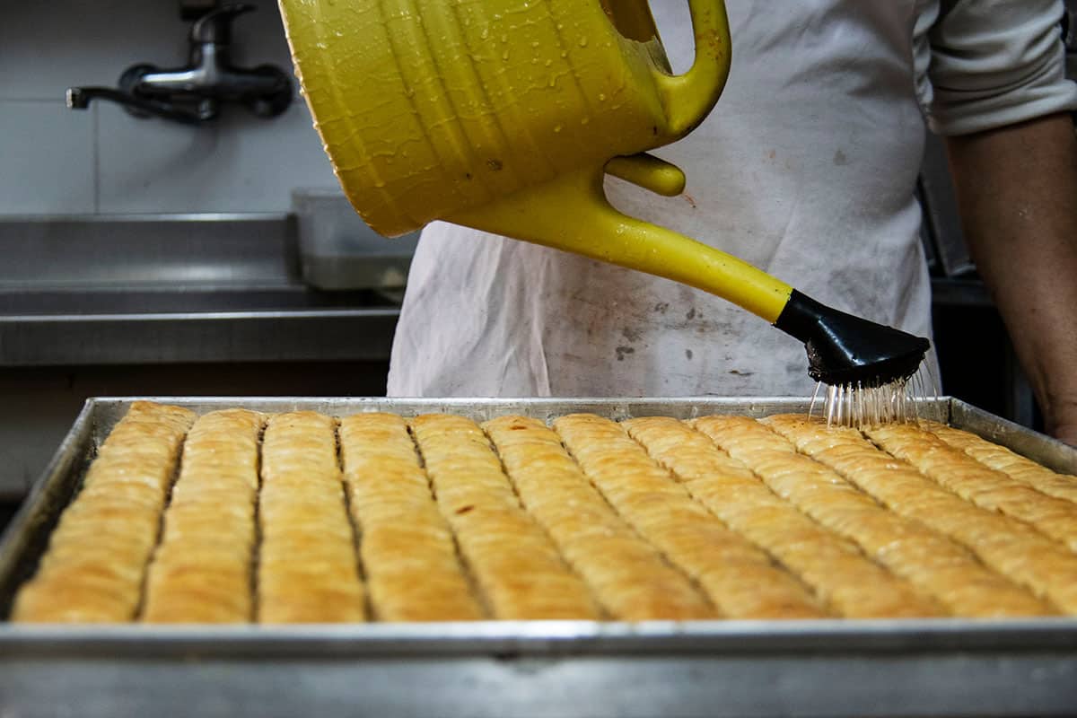 a chef pours sugar water on a baklava