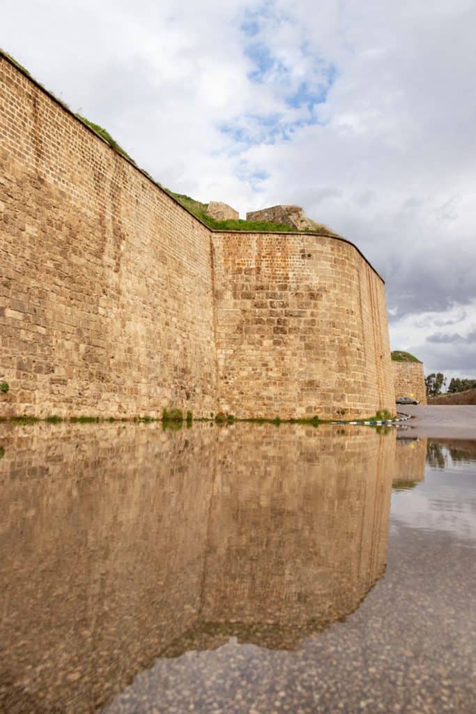 Akko's walls reflection in a paddle of water