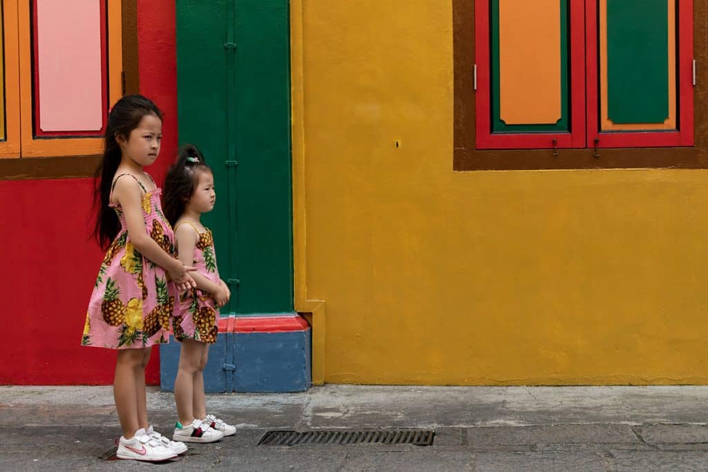girls are modeling in front of a colorful building in Singapore