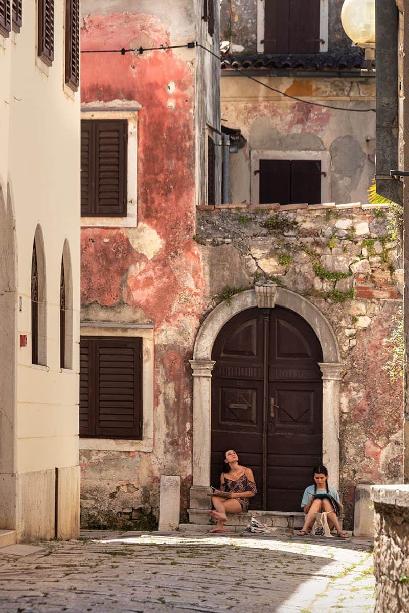 Girls sitting and drawing against a beautiful ancient wall