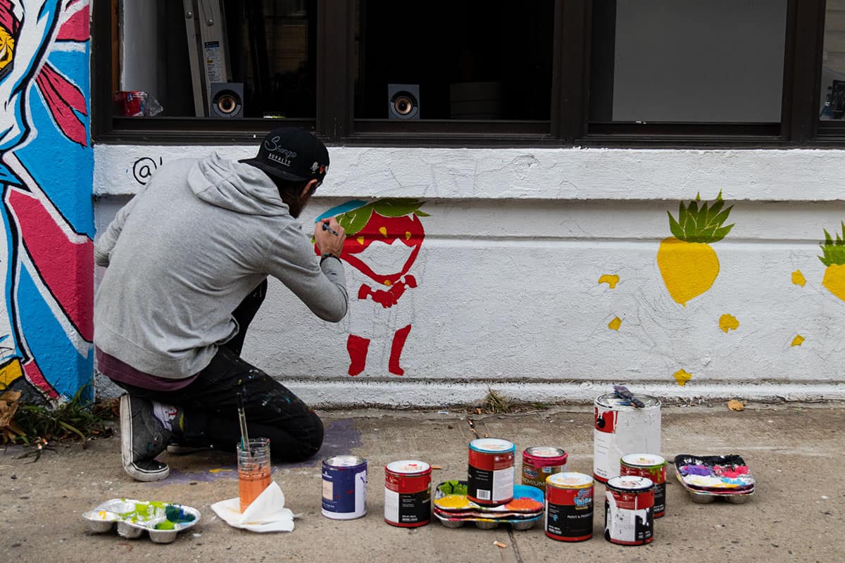 An artist is painting on one of Bushwick's wall