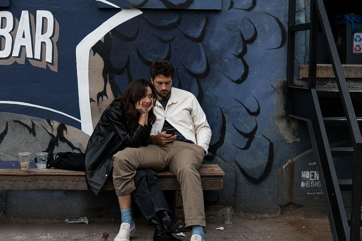 A couple sitting next to a colorful graffiti in Bushwick streets NYC