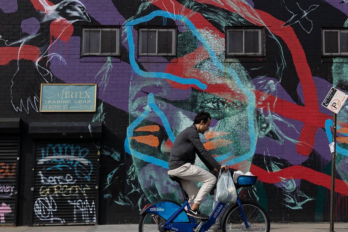 A man riding a bicycle against a graffiti background in Brooklyn