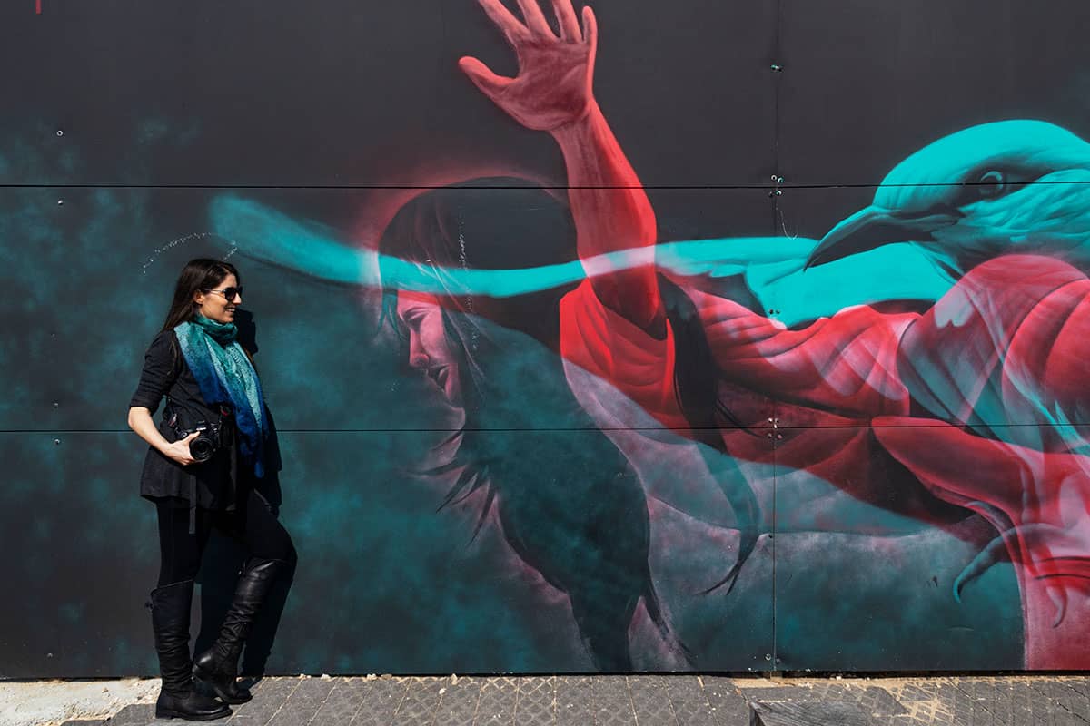 אישה נשענת על ציור קיר ביפו תל אביב